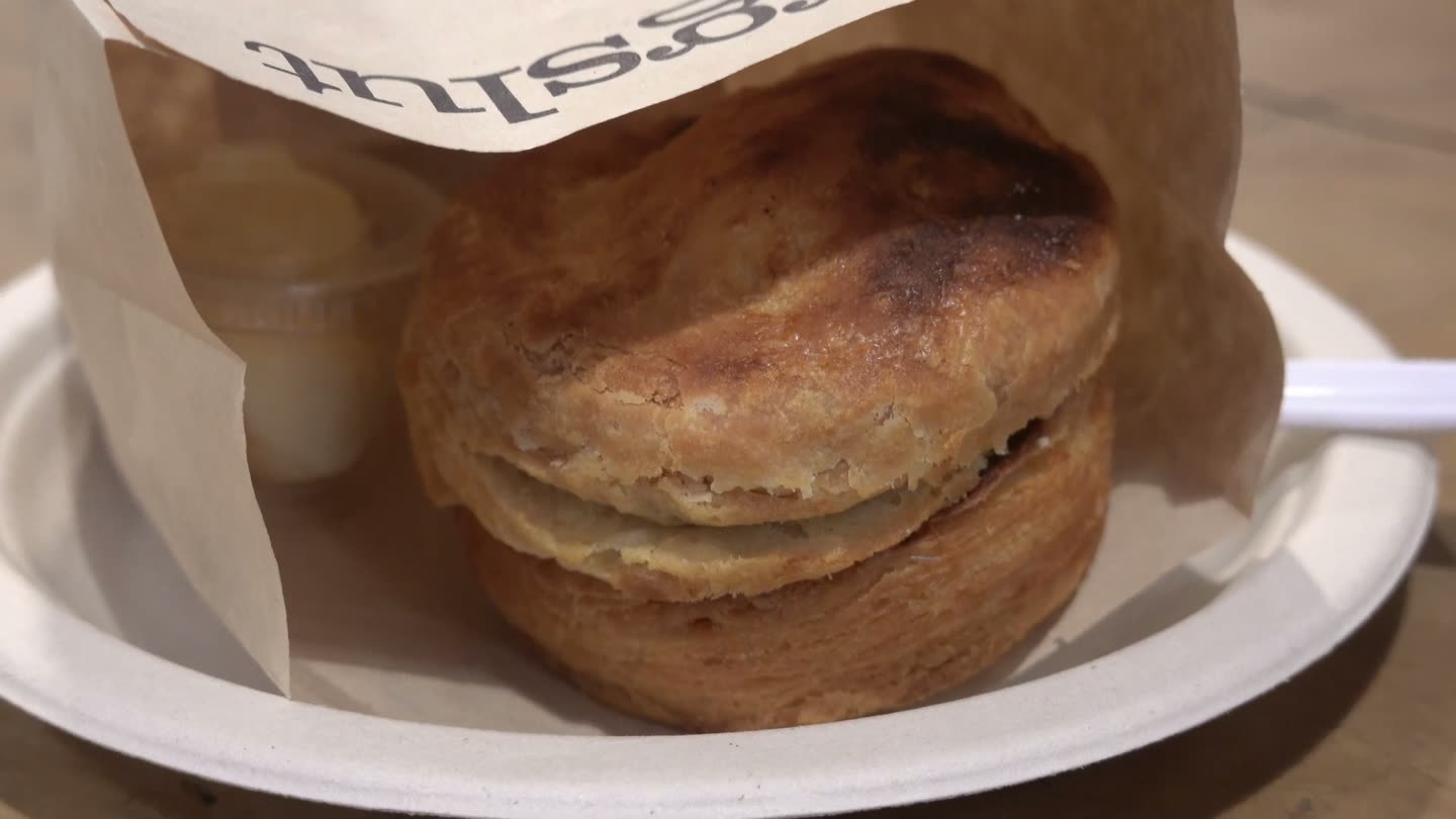 A tall, golden buttermilk biscuit in an Eggslut paper wrapper