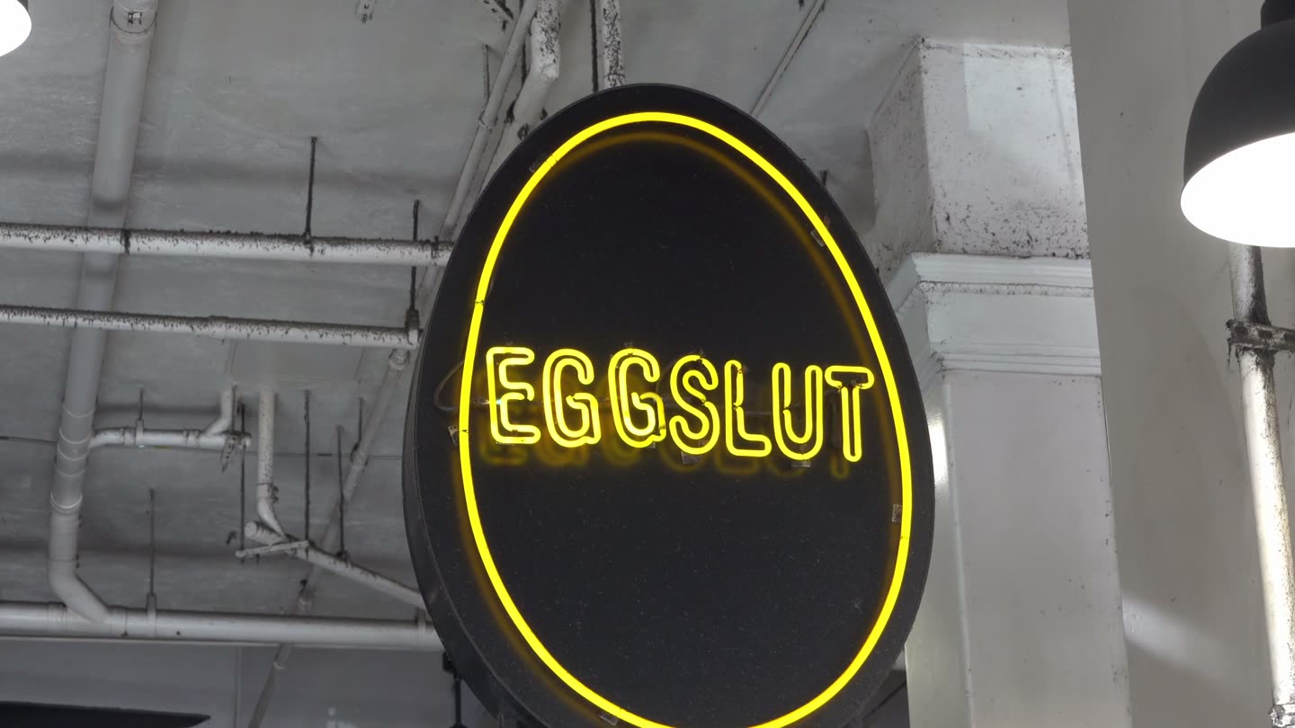 The round yellow Eggslut neon sign above its counter