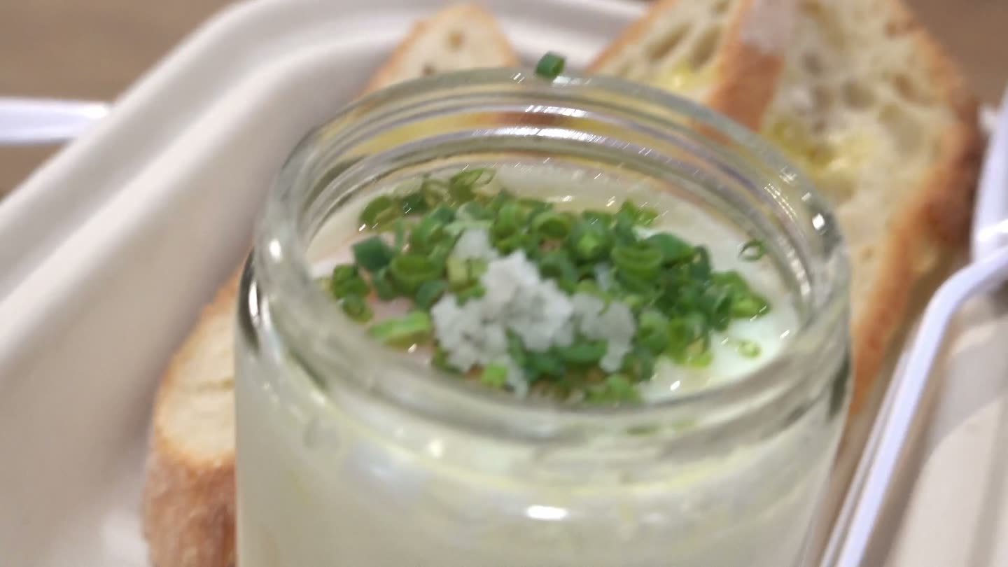 Eggslut's Slut: a glass jar of coddled egg over potato puree topped with chives and sea salt, with toasted baguette slices