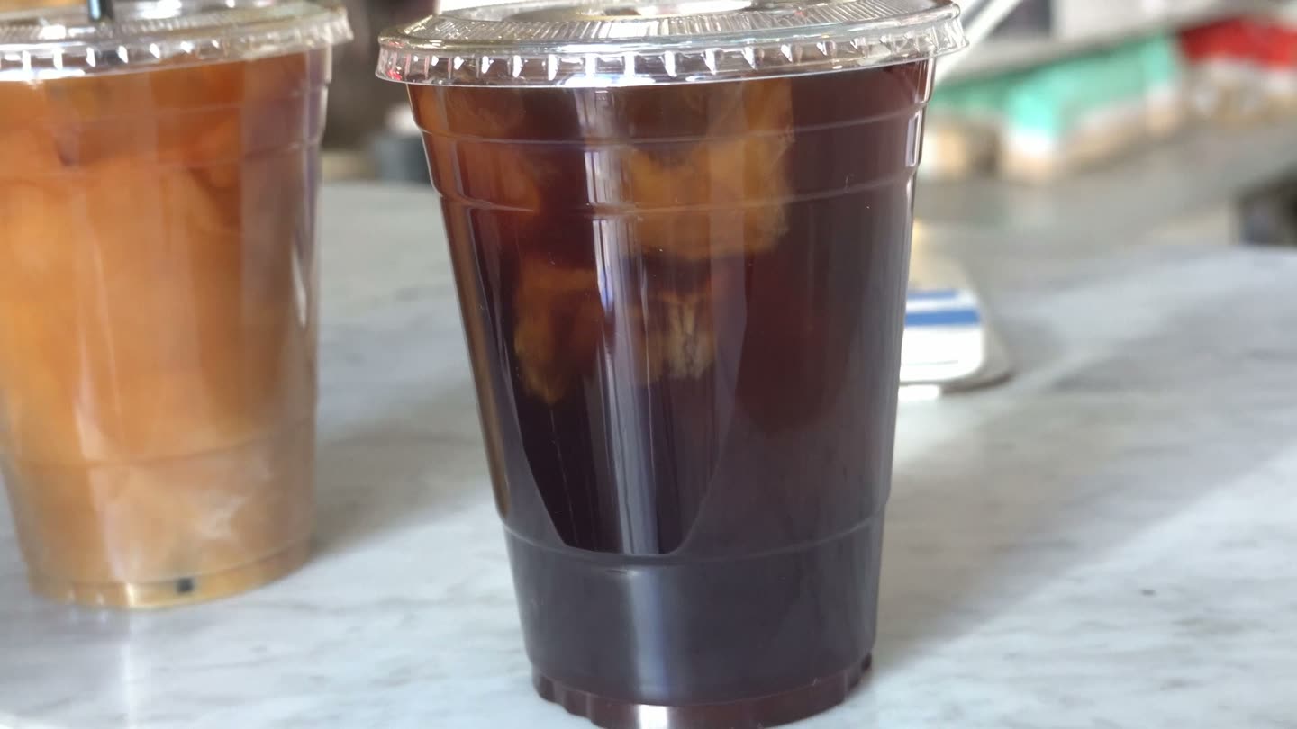Two iced coffees, one with oat milk, on a marble counter