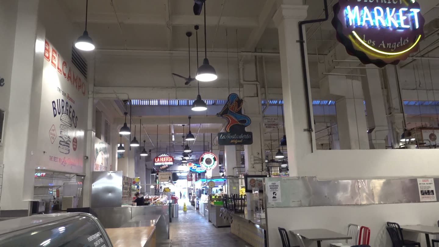 The long center aisle of Grand Central Market early in the morning, with neon signs and almost no one in line