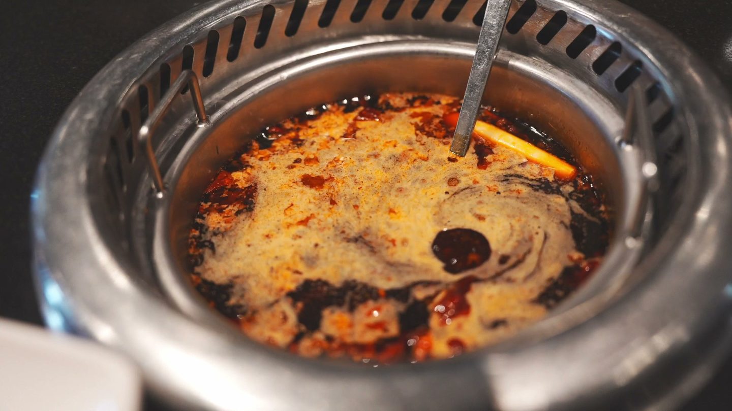A small hot pot of red Chongqing beef tallow broth bubbling in its burner
