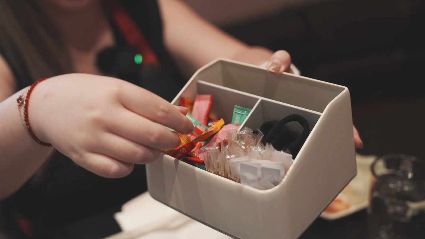 A small caddy at the table with hair ties and wrapped candy