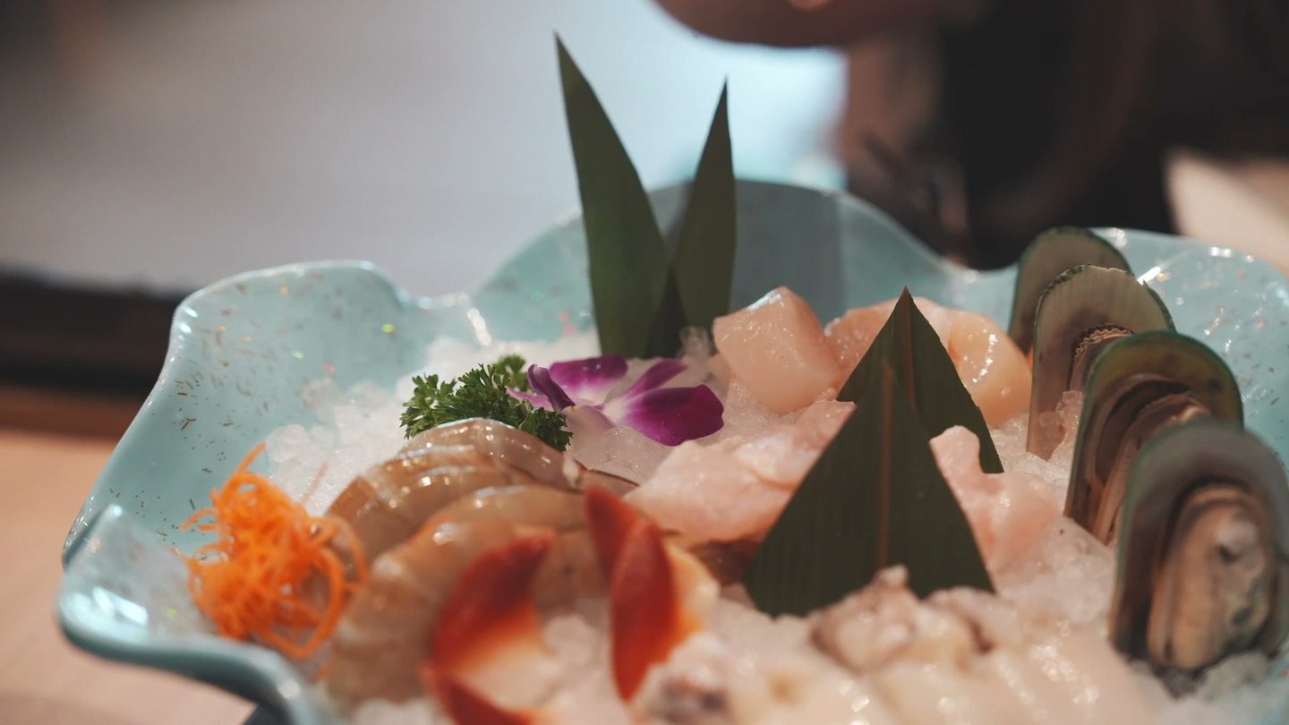 Haidilao seafood platter on ice with shrimp, mussels, fish fillet, squid, and orchids