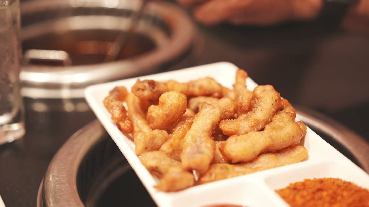 A plate of golden Sichuan crispy pork strips with ketchup and chili dipping powder