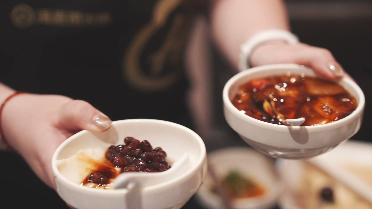 Bowls of tofu pudding topped with red beans and brown sugar syrup