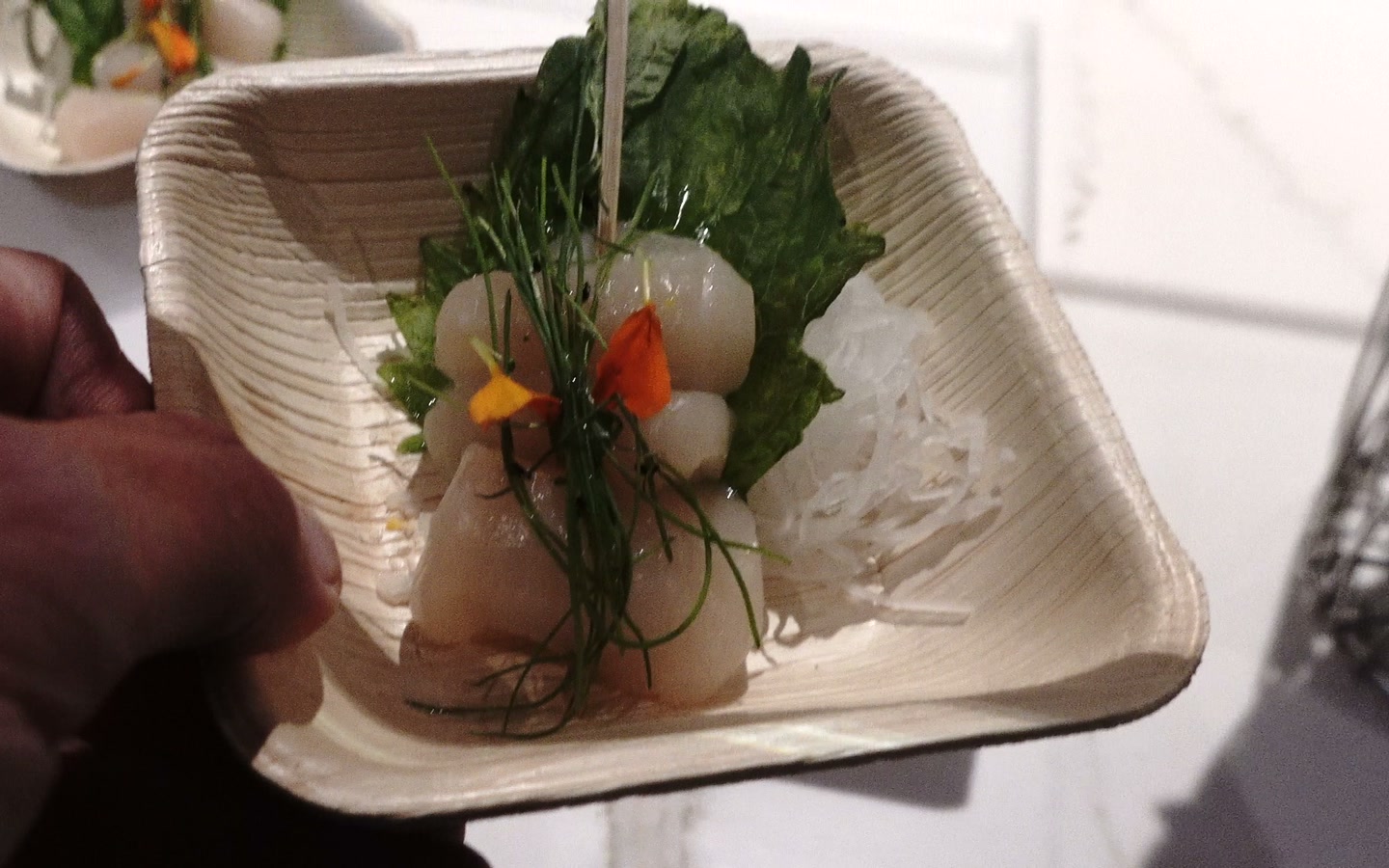 Scallop appetizer with greens in a small dish in the floor lounge at Intuit Dome