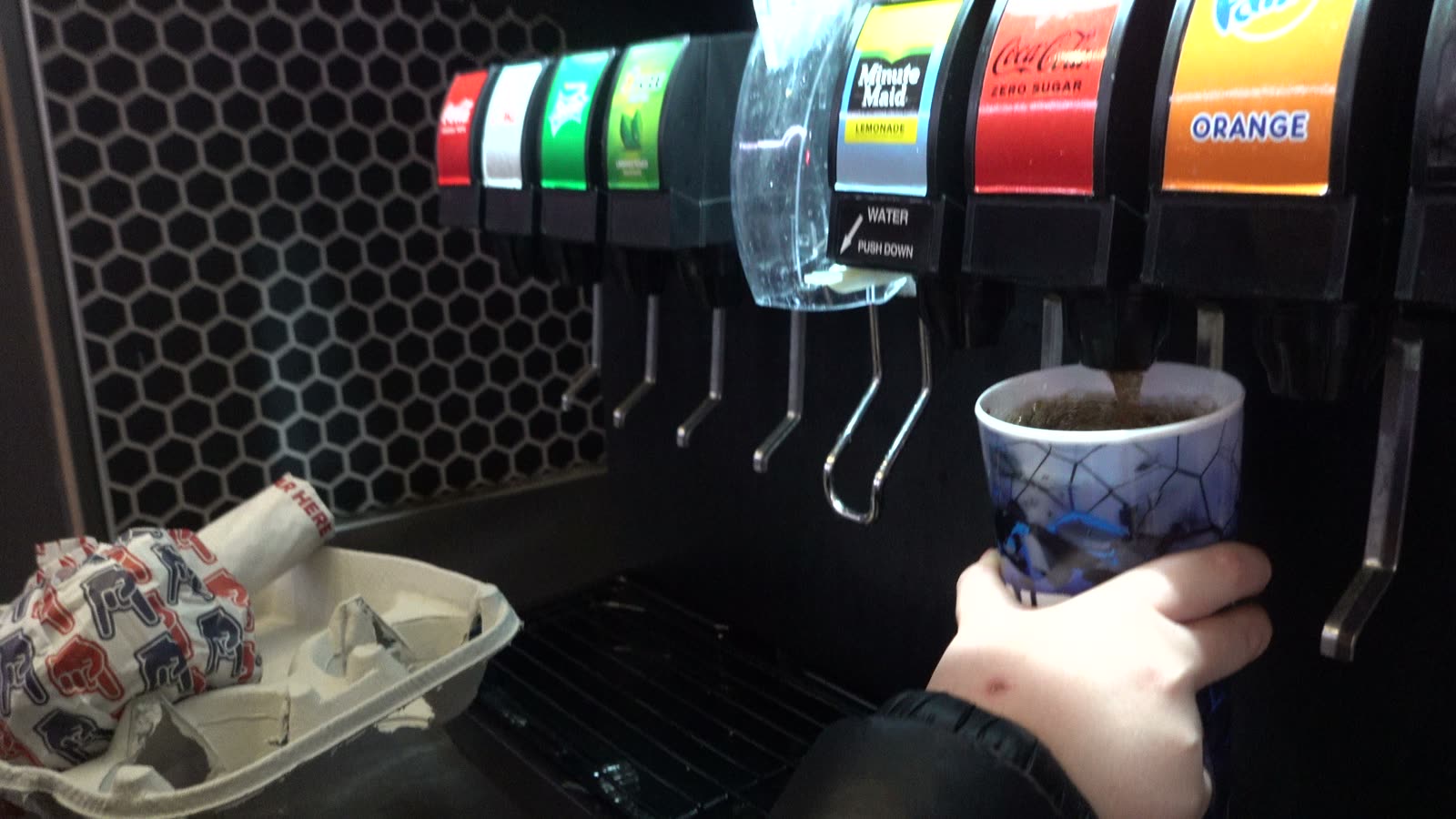 Filling a refillable souvenir cup at a self-serve soda fountain at Intuit Dome