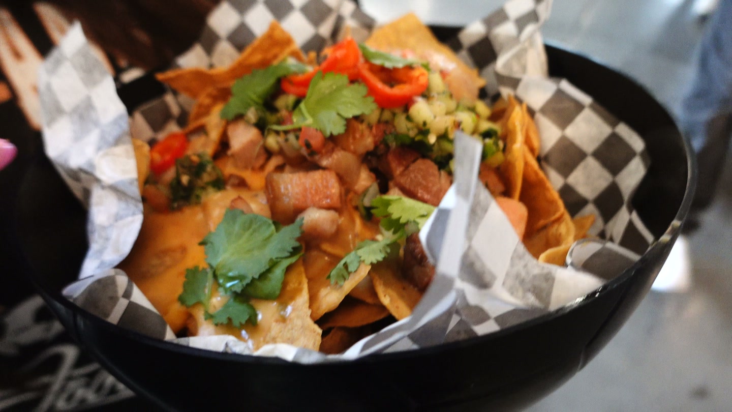 Close-up of the K-BBQ pork belly nachos held by Lisa at BMO Stadium.