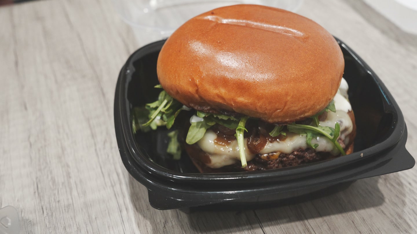 Primal Cuts burger with cheese, onions, and arugula.