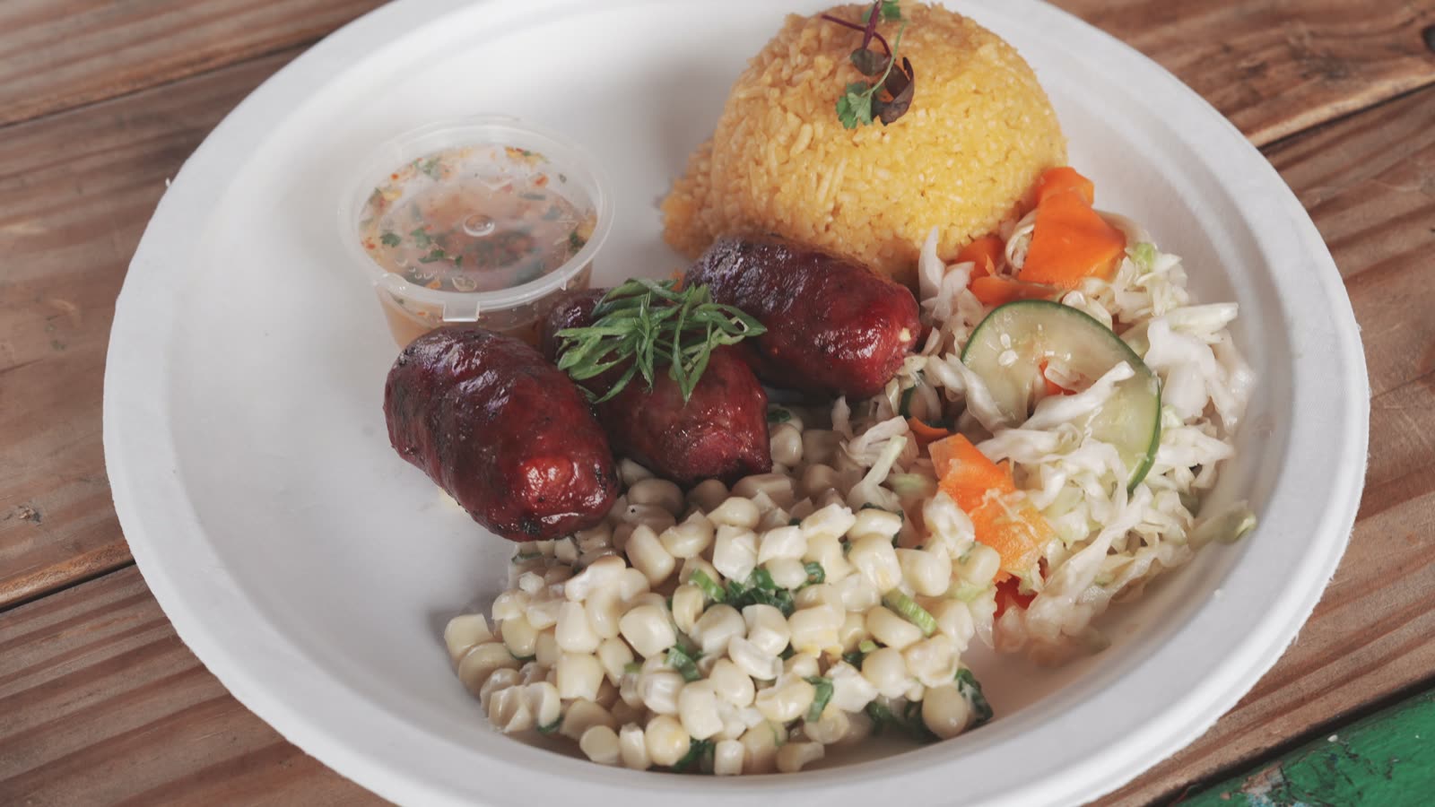Kreung LA sausage plate with three grilled sausages, corn salad, cabbage, coco-lime leaf rice, and dipping sauce