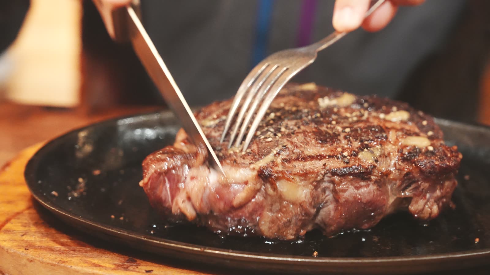 A rare New Zealand Scotch fillet steak being cut on a sizzling plate at Angus Steak House