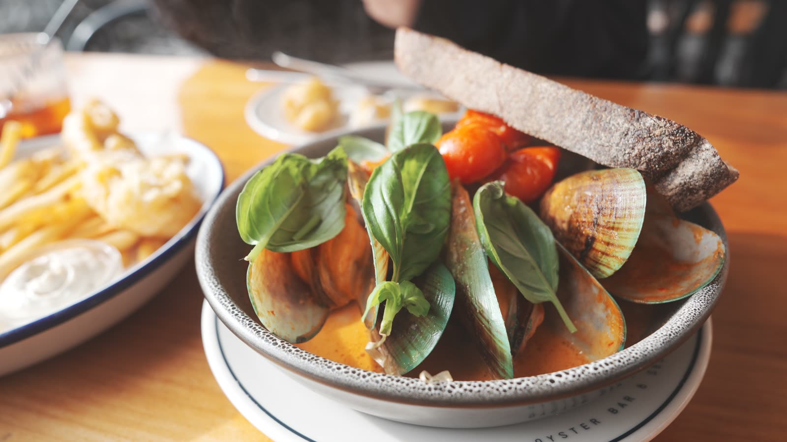 New Zealand green-lipped mussels in a creamy tomato sauce with basil and bread at The Shucker Brothers