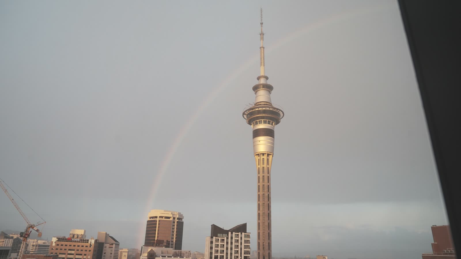 Auckland's Sky Tower with a faint rainbow behind it
